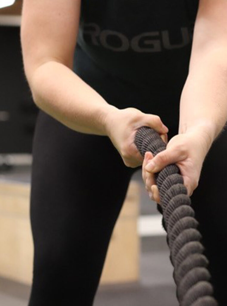 Frau trainiert im Fitnessstudio mit einer Battle Rope