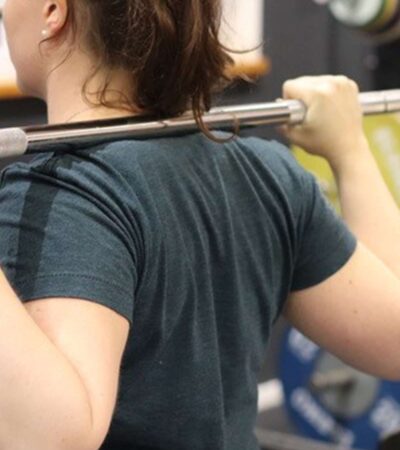 Junge Frau beim Heben einer Langhantel im Fitnessstudio